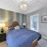 Modern bedroom with grey feature wall and ensuite bathroom.