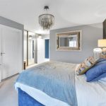 Modern bedroom with grey accents and decorative mirror.