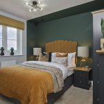 Modern bedroom with green walls and yellow bedspread.
