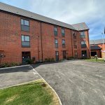 Modern brick residential building with parking area.