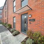 Modern brick building entrance with pathway and plants.