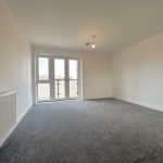 Empty room with grey carpet and large windows.