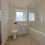 Modern bathroom with bath, sink, and heated towel rail.