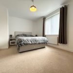 Minimalist bedroom with double bed and beige carpet.