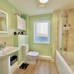 Modern bathroom with green walls and tiled bath.