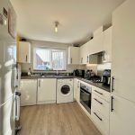 Modern kitchen with white cabinets and appliances.