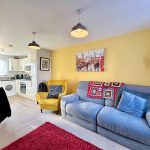 Cosy living room with yellow wall and grey sofa.