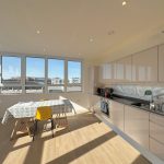 Modern kitchen with dining table and large windows.