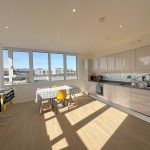 Modern kitchen with large windows and dining area.