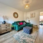Modern living room with green sofa and wooden flooring.