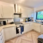Modern kitchen with white cabinets and appliances.