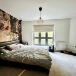 Modern bedroom with abstract wall art and large window.