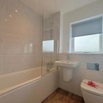 Modern bathroom with bathtub and window with blind.