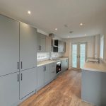 Modern grey kitchen with wooden floor.