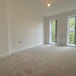 Spacious empty room with carpet and large windows.