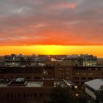 Sunset view over city buildings with colourful sky.