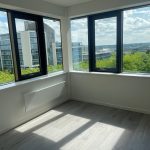 Bright empty room with large windows and city view.