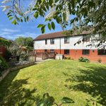 Spacious garden with sunny lawn and patio area.