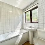 Bright bathroom with bathtub, sink, and toilet.