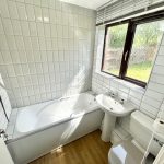 Modern bathroom with bathtub, shower, sink, and toilet.