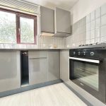 Modern kitchen with oven and grey cabinets.