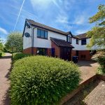 Semi-detached house with garden and clear skies.