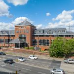 Large brick office building with road in foreground.
