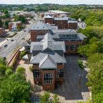 Aerial view of brick building and surrounding greenery.