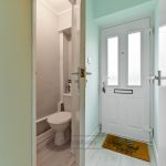 Entrance with toilet door ajar and welcome mat.