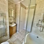 Modern bathroom with shower and tiled walls.