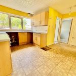 Spacious kitchen with yellow walls and large window.