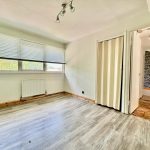 Bright empty room with wooden floor and windows.