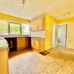 Spacious kitchen with yellow walls and large window.
