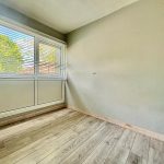 Empty room with large window and wooden floor