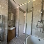 Modern bathroom with shower and tiled walls.