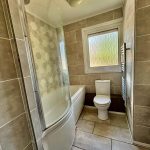 Modern bathroom with tiled walls and curved bathtub.