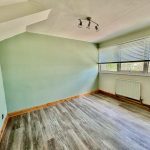 Empty room with hardwood floor and large windows.