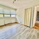Empty room with laminate flooring and large window.