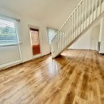 Spacious room with wooden floor and staircase.