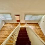 View from stairs with wooden floor and windows.