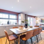 Modern dining room with table and chairs, kitchen view.