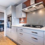 Modern kitchen with sleek appliances and wooden floor.