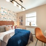 Modern bedroom with patterned wallpaper and desk area.