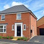 Modern red brick house with garage and garden.