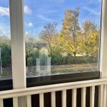 View of autumn trees through a window indoors.