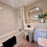 Modern bathroom with round mirror and white tiles.