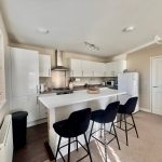 Modern kitchen with white cabinets and island bar.