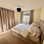 Bright bedroom with double bed and curtains.