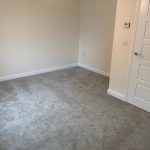 Empty room with grey carpet and white door.