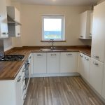 Modern kitchen with white cabinets and wooden countertops.